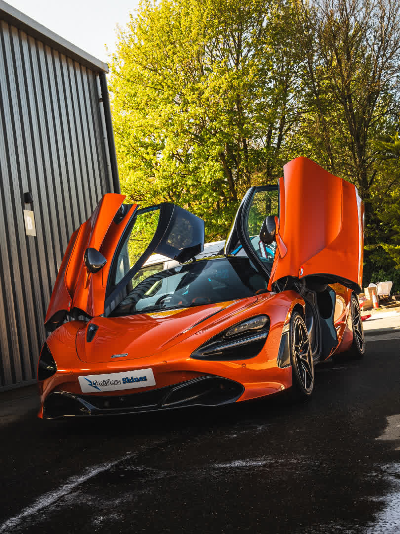 Orange McLaren 720S with doors up after a maintenance wash